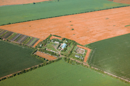 Aerial drone shot of farmhouse among green fields in British countryside. Birds eye view of harvest...
