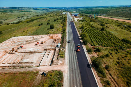 Aerial top view of roadworks with road workers lay asphalt. Work on laying of asphalt. Aerial photography. The repair of the road. The view from the topの写真素材