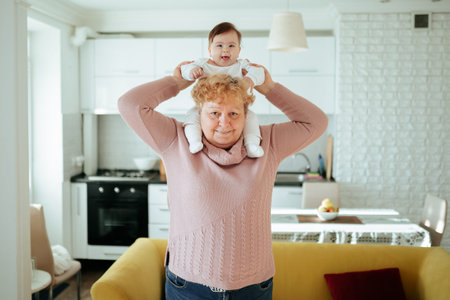 Tender affectionate older grandma hugging cute baby granddaughter. elderly female holding her grand kid on the back playing, at home lovely family slow motion footageの写真素材