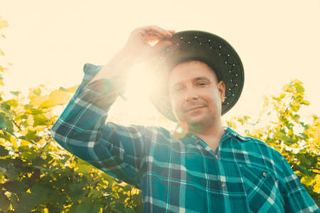 top view of male farmer vinified looking at camera in vineyard. young male with hat on a sunny summer day.の写真素材