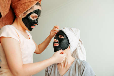 Woman apply paper black mask skin care. cosmetic procedures, mask for skin care, woman young, spa salonの写真素材