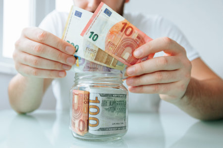 close up view of male hand show pounds and euro banknote, glass jar. man saving in jars