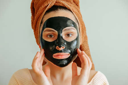 girl with black cosmetic mask looking at camera touches her mask with her hand. close upの写真素材