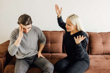 Angry wife cries out to her husband, who covers his ears with his hands. family crisis conflict concept. Unhappy young Caucasian man think of divorce breakup after family quarrel.の写真素材