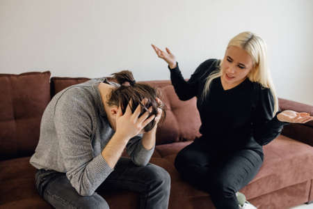 man with his hands on his head while his wife verbally intimidates him. Aggressive woman keeps her husbands morale. Relationship Crisis Conceptの写真素材