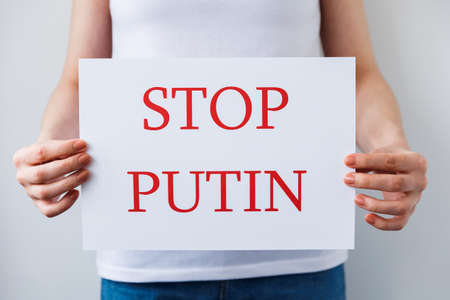 close up of a Protester hands holding cardboard Banner with the words stop putin. protesting against the Russian invasion. banner inscription cardboard massage Hands Off Ukraine.の写真素材