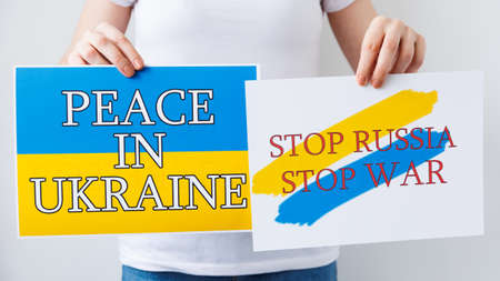 close up of a woman hands is holding a poster with the image of the Ukrainian flag, which says free ukraine stop war . Rally against the war, Protester hands holding cardboard Bannerの写真素材