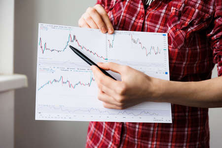close up of a woman hands explains how to trade on the exchange. It shows on the chart, Business and education concept.の写真素材