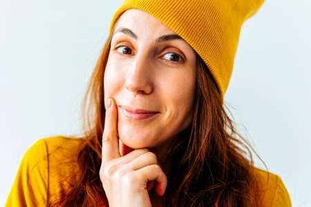 portrait of a hipster girl young woman teenage girl finger in her mouth with yellow hat on her head, looking at the camera and smiling slightly.の写真素材