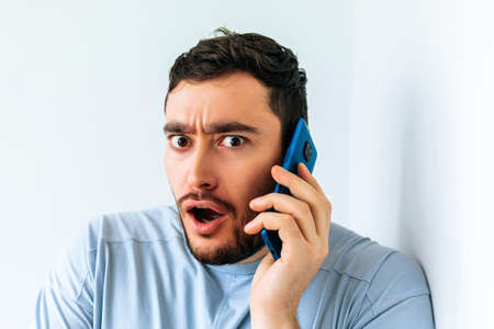 Young bearded man talking on the phone at home shocked expression of fear, scared male in shock with a surprise face, afraid and excited with fear expressionの写真素材