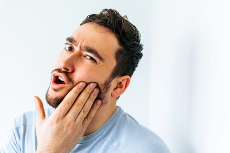 close up of a hoary young man over isolated background touching mouth with hand with painful...