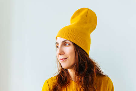 portrait of a hipster girl young woman teenage girl with yellow hat on her head, looking smiling slightly.の写真素材