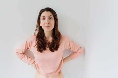 woman looks with a happy expression on his face and does not believe what he saw looking at camera isolated on light gray backgroundの写真素材