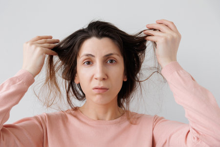 Woman showing hair problems Depressed and Worried. female feels upset about brittle damaged dry hair loss concept. Women hormone problems or vitamins deficiency.の写真素材