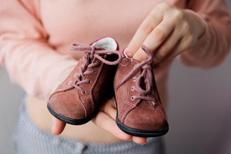 Close up, childrens crimson shoes. Birthday gift. Female hands showing baby little girl shoes. for newborn girl in mother hands. shoes for children.の写真素材
