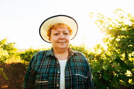 portrait of winemaker woman with hat looking at camera at sunset. nice old Italian female farmer.の写真素材