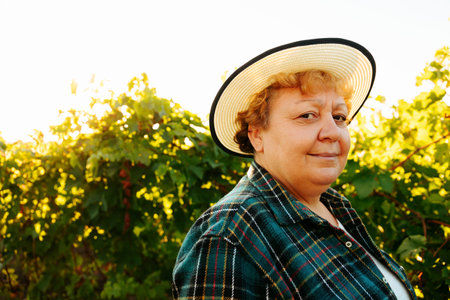 Farmer woman smiling and looking at camera, has hat on her head is happy, winemaker in her vineyard.の写真素材