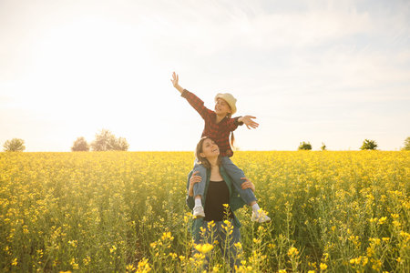 Gorgeous farmer family smiling daughter on mother shoulders in sunset. Lovely mother and daughter...