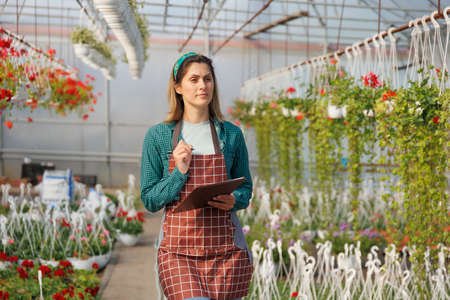 american Scientist woman with holding book of flower during research experiment in flower garden. Female gardener in a greenhouse analyzing some flowers, copy spaceの写真素材
