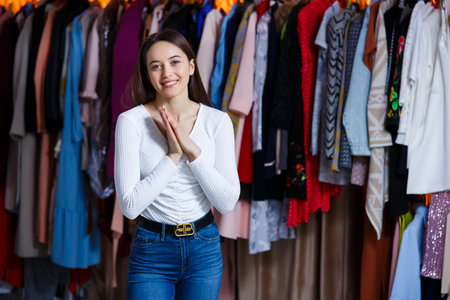 Front view looking at camera joyful happy teen girl hold hand near anticipation grand shopping. The girl who shopped at the store wants to quickly examine all the things hanging on hangers.の写真素材