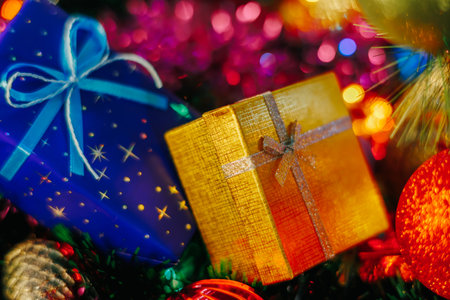 Close up of a blue gift box with stars tied with a blue bow with a rope. The radiance of garlands, multi colored, blurred background. Selective focus. Bokeh.の写真素材