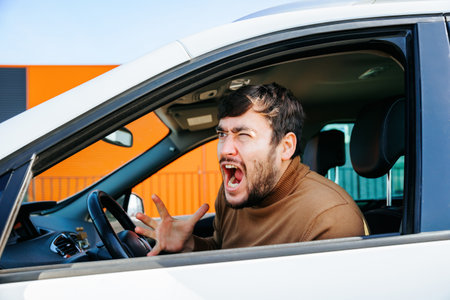 americandisturbed and furious bearded chauffeur man gesticulates and yelling in the interior of a car. person male annoyed and stressed middle age people, profile viewの写真素材