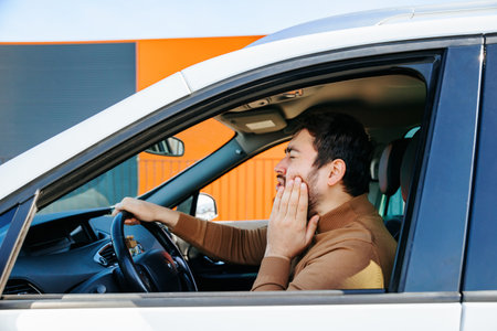 Caucasian disturbed bearded chauffeur man he has toothache in the interior of a car. male person suffering annoyed and stressed middle age people, profile view, in the car, healthcare andの写真素材