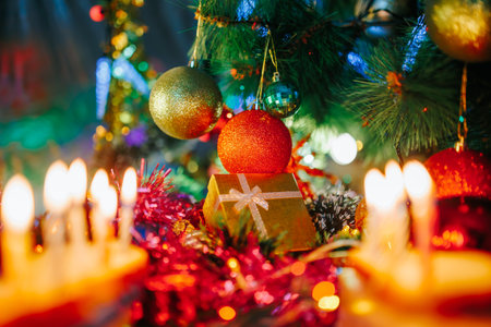 Christmas decorations of different colors with glitter hang next to the gift box. Tinsel lies under the balls and glitters from the lights of the garland. selected focus.の写真素材