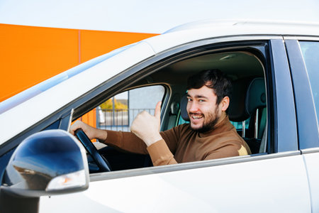 joyful bearded Caucasian man showing thumb up and looking at the camera is in the car. driver smiling male happy handsome. very cheerful manの写真素材