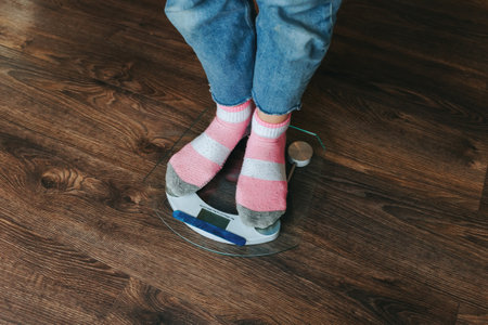 Close up body part women, legs on scales, girl weighing, obsession with excess weight, top view, at home. Woman learns her weight. Slimming concept, health monitors.の写真素材