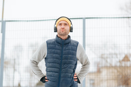 A young male is seen participating in outdoor athletic activities during wintertime, wearing headphones and performing gymnastic movements.の写真素材