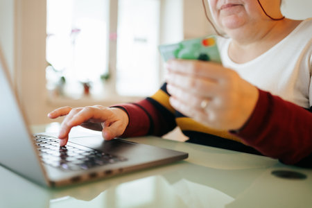 A close-up of a female hand making a purchase through e-commerce on a laptop, using a credit card. seamless process of online shopping, with a focus on the hands, laptop and credit card in use.の写真素材