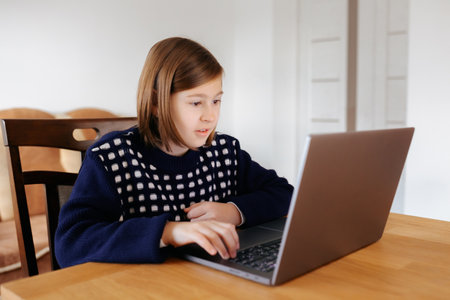 An excited young gamer kid playing with her laptop at home, completely immersed in the virtual world.の写真素材