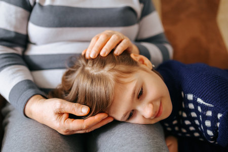 close up beautiful image of a grandmother and granddaughter sitting together on the couch hands on head, engaged in a deep conversation and strengthening their relationship.の写真素材