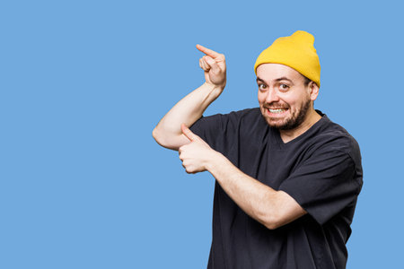 an caucasian and emotional man pointing to free space is captured while looking at the camera, in a moment of pure joy and excitement, his expressive gestures, studio shot with copy space,の写真素材