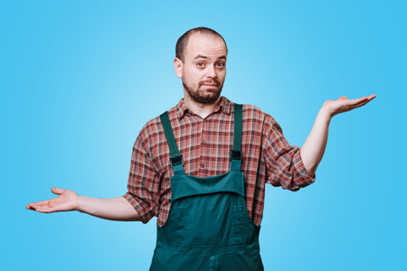 A young man with surprised hands who appears to be puzzled and expresses this emotion through his facial expression and body language looking at camera. studio shot on the blue background, copy spaceの写真素材