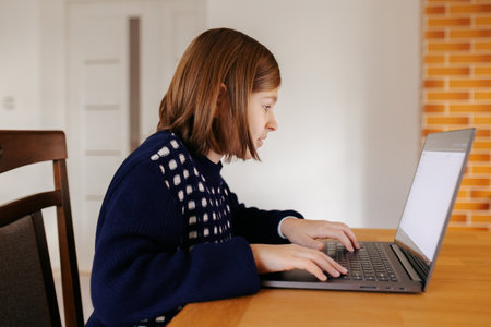 A young girl gamer playing online with intense focus and excitement, eagerly trying to level up and conquer new territoriesの写真素材