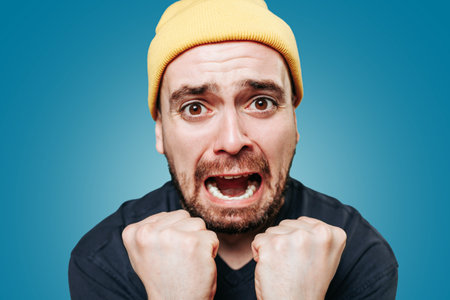 A studio shot of a shouting guy, his expression one of anger and irritation as he looks directly at the camera and lets out a violent scream. close upの写真素材
