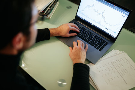 An intense close-up of a brokers hands on a laptop keyboard at home in the nighttime, as they analyze market data and make trading decisions.の写真素材