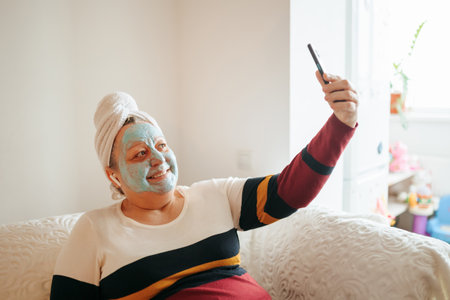Real Women Relax and Recharge A Seniors Skincare Selfie An elderly woman at home takes a satisfying selfie while indulging in a relaxing skincare routine. authentic image of real people and real joyの写真素材