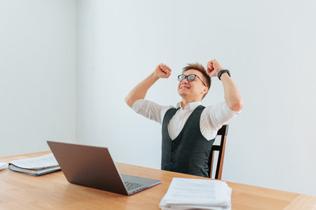 A white collar worker stands his arms raised in celebration as he The satisfaction and happiness he feels after a long days work is palpable.の写真素材