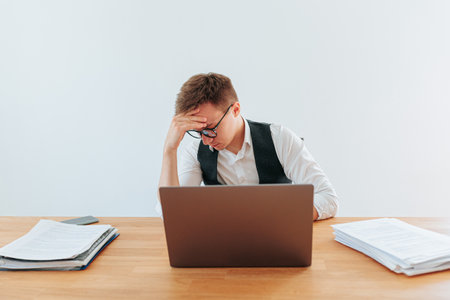 A man with glasses looks upset and tired as he works late into in his home office, suffering from the symptoms of burnout and depression. Burnout and Isolation The Troubled Home Officeの写真素材