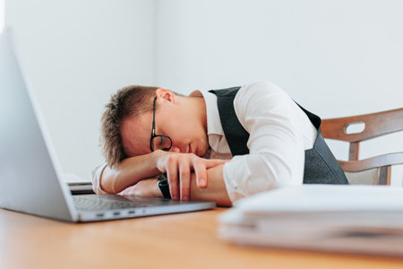 A white-collar worker dozes off while reading a report, seeking a brief escape from the pressures of the workplace and the demands of the job. The Science of Sleep How Napping Improves Performanceの写真素材