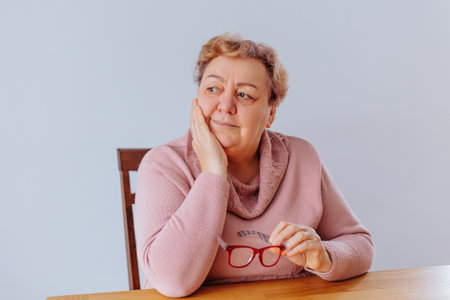 Senior Womans Authentic Portrait in Eyeglasses at Home, A senior woman at home, captured in a striking portrait that showcases her inner strength and resilience in the face of adversity.の写真素材