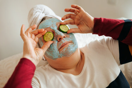 A senior woman indulging in a relaxing skincare routine while listening to music through her earphones. The authentic and real photo showcases the womans overweight physique, with a cucumber sliceの写真素材
