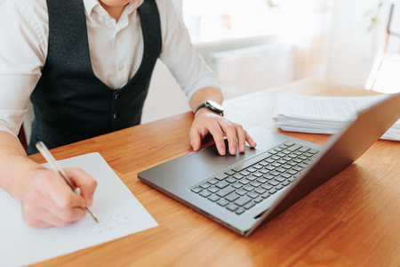 A top view shot of a mans hands holding a pen and writing on a paper in his office workspace, with a close-up of the handwritten text on the paperの写真素材