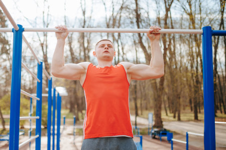 Graceful Gymnast Doing Pull-Ups on High Bar for Athletic Training. A male gymnast is practicing his routine on the high bar, performing multiple pull-ups with ease and grace.の写真素材