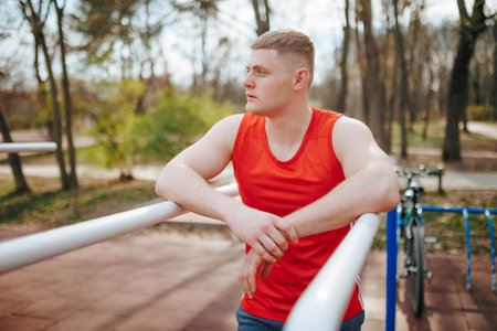 Red T-Shirt and Sportswear on a Young Athlete A Portrait of Strength and Style Outdoors. Portrait of a Stylish Young Guy in Authentic Red Sportswear A Model of Youth and Confidence Outdoorsの写真素材