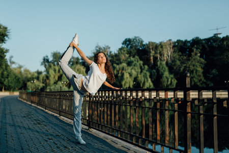 Young and Fit Teen Stretching and Sporting Outdoors. a young girl doing exercises in the park. Youthful Vitality Teen Stretching and Exercise Outdoorsの写真素材