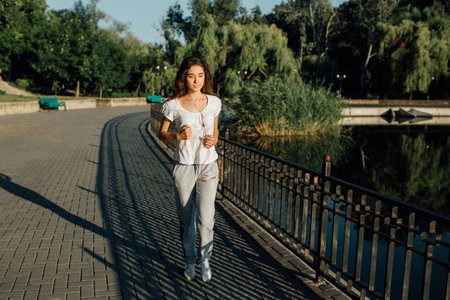 Teen Runner Pounding the Pavement in Her Fitness Journey. Winner as style of life. Horizontal shot of young beautiful woman in sports clothing smiling while passing finish line during jogging.の写真素材